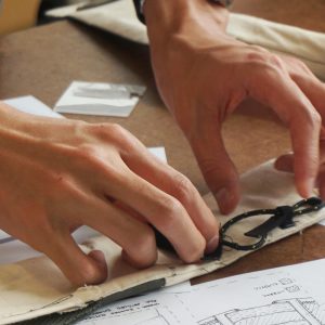 a designer's hands work on a soft goods prototype